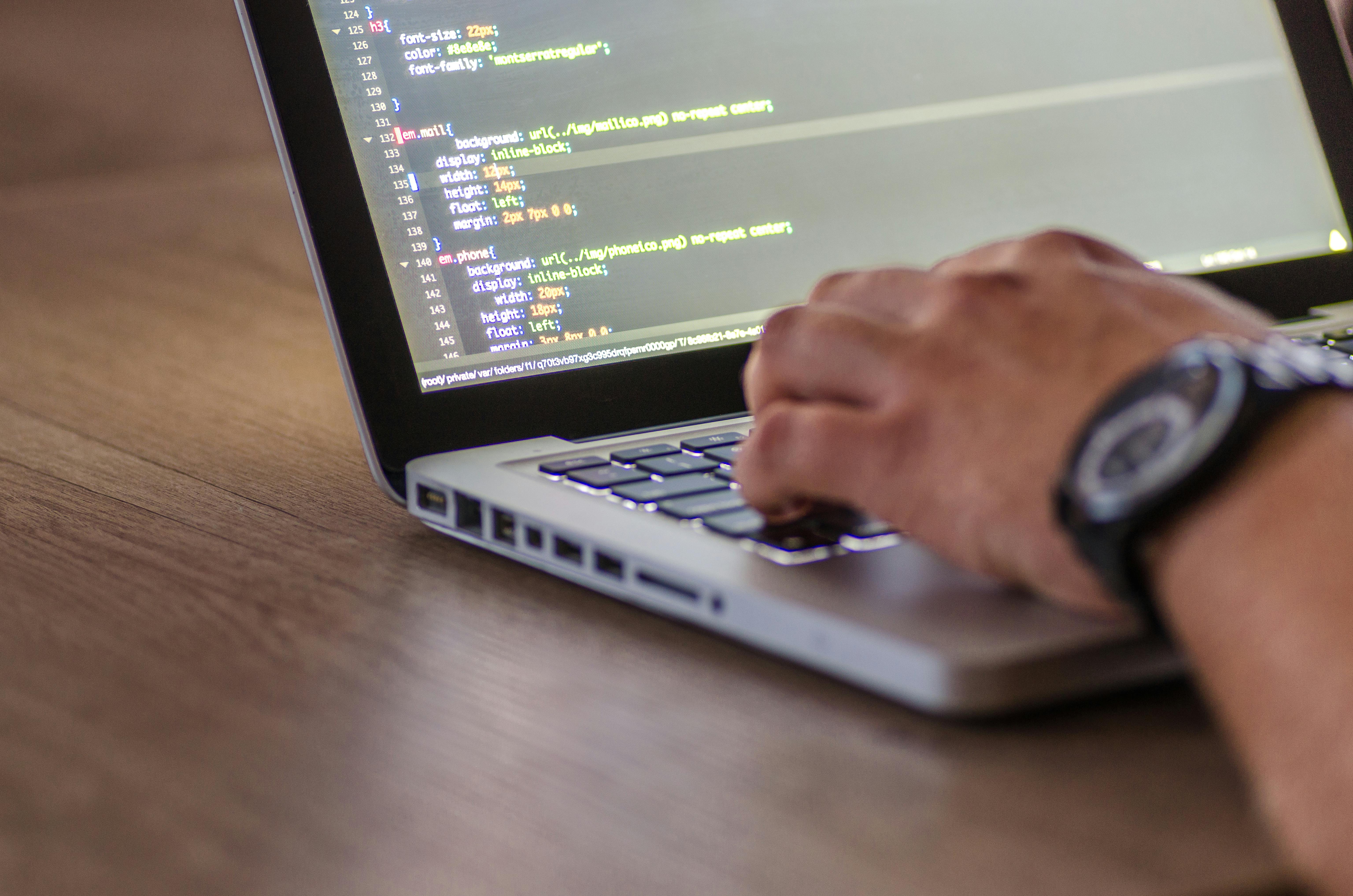 Persona escribiendo código en un portátil, representando desarrollo de software